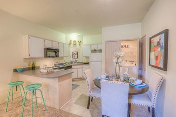 A kitchen with a bar stool and a dining table set for two.